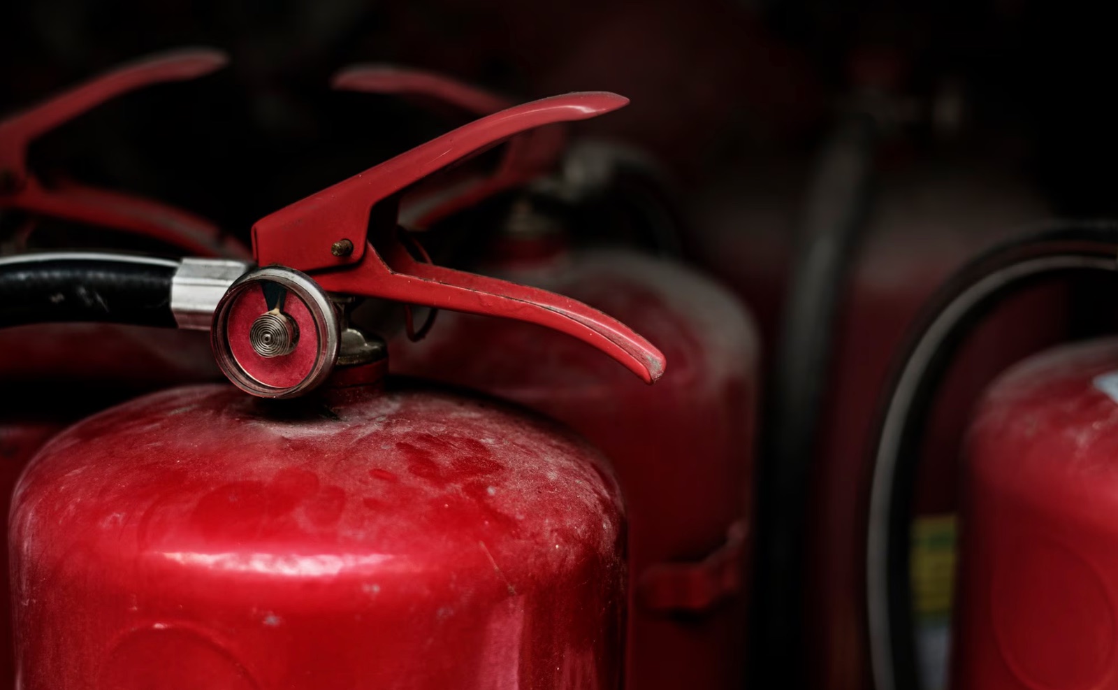 Red fire extinguishers lined up against a wall